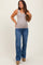 woman wearing a light brown ribbed maternity tank top and blue flared jeans, showing her baby bump