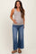 woman wearing a light gray ribbed maternity tank top and distressed wide-leg jeans, gently holding her baby bump