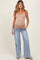 woman wearing a nude maternity tank top and light blue wide-leg jeans, showing her baby bump