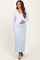 woman wearing a light blue long sleeve maternity dress with ribbed detailing and holding her baby bump