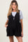 woman wearing a black maternity overall dress with a grey t-shirt underneath and pockets, showcasing a baby bump