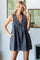 woman wearing a dark denim sleeveless babydoll dress with a tie detail and pockets