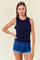 woman wearing a navy blue sleeveless top with ruffle details and paired with denim shorts