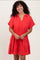 woman wearing a bright red short sleeve dress with a collared neckline and tiered ruffle hem