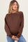 woman wearing a brown oversized maternity sweatshirt and cradling her baby bump