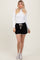 woman wearing a fitted white long sleeve top and black sporty shorts with a drawstring waist and white trim