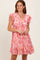 woman wearing a pink floral ruffled mini dress with short sleeves and a flared hem