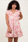 woman wearing a pink floral print short sleeve dress with ruffles and a tiered skirt design