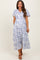 woman wearing a blue and white floral maternity dress with short sleeves and a v-neckline, showing her baby bump