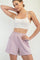 woman wearing a beige cropped tank top and light purple high-waisted shorts with pockets