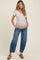 woman wearing a light beige short sleeve maternity top with a visible baby bump and blue relaxed jeans
