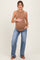 woman wearing a tan ribbed maternity tank top and blue flared jeans, holding her baby bump