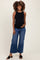 woman wearing a black maternity tank top and blue wide-leg jeans, gently holding her baby bump