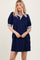 woman wearing a navy blue short sleeve puff dress with striped collar and cuffs