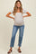 woman wearing a light gray short sleeve maternity top and distressed blue maternity jeans, showcasing her baby bump