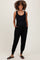 woman wearing a black maternity jumpsuit with a scoop neckline and side pockets, showing her baby bump