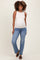 woman wearing a light beige maternity tank top and blue jeans, showing a visible baby bump