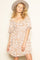 woman wearing a cream and rust floral print short dress with puff sleeves and a scoop neckline, accessorized with a hat