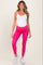 woman wearing a white maternity tank top and bright pink maternity leggings, showcasing a visible baby bump