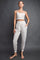 woman wearing a light gray crop top and matching jogger pants with side pockets