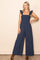 woman wearing a navy blue sleeveless jumpsuit with ruffle straps and wide leg pants