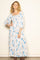 woman wearing a light blue floral maxi dress with long sleeves and a smocked bodice