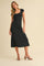 woman wearing a black fitted midi dress with cap sleeves and a square neckline, standing in a neutral background