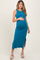 woman wearing a teal sleeveless maternity maxi dress with a side slit and holding her baby bump