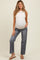 woman wearing a light beige sleeveless maternity top and gray wide-leg maternity jeans, showing her baby bump