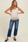 woman wearing a beige v-neck maternity tank top and distressed blue maternity jeans, showing her baby bump