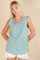 woman wearing a mint green sleeveless top with a button detailing and styled with white distressed shorts