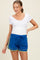 woman wearing a white scoop neck maternity top and blue athletic shorts with yellow trim