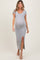 woman wearing a gray short sleeve maternity dress with a side slit and a visible baby bump