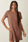 woman wearing a short sleeve brown ribbed t-shirt dress standing with one hand on her hip