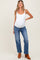 woman wearing a white maternity tank top and blue wide-leg maternity jeans, showcasing her baby bump