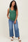 woman wearing a green maternity tank top and blue wide-leg jeans, showing her baby bump