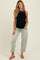 woman wearing a black maternity tank top and light green rolled-up maternity jeans, showing her baby bump
