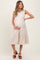 woman wearing a beige sleeveless maternity dress with buttons and tiered ruffles, holding her baby bump