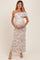 woman wearing a pastel floral print off-the-shoulder maternity dress and holding her baby bump
