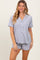 woman wearing a gray short-sleeve pajama set with buttons and contrasting white trim