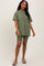 woman wearing an oversized olive green t-shirt with matching bike shorts and tan slip-on shoes