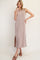 woman wearing a beige ribbed maxi dress with side slits and smiling while posing