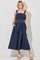 woman wearing a navy blue maxi dress with a drawstring waist and oversized straps, standing with pockets and open-toe sandals