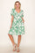 woman wearing a green floral print knee-length dress with short sleeves and pockets
