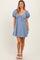 woman wearing a light blue striped puff sleeve dress with a tie front detail and a flared skirt