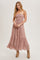 woman wearing a dusty pink strapless maxi dress with a smocked bodice and tiered hem, paired with tan ankle boots