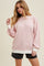 woman wearing a light pink oversized sweatshirt with white cuffs and a relaxed fit paired with black shorts