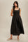woman wearing a black sleeveless maxi dress with a fitted bodice and gathered skirt, standing in a neutral background