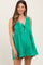woman wearing a green maternity romper with pleats and a tie-front detail, showcasing her baby bump
