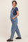woman wearing a navy t-shirt and light blue maternity overalls, standing with a relaxed pose